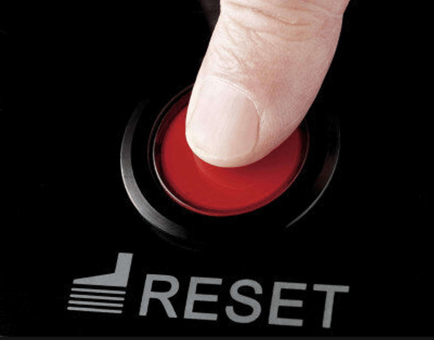 A finger touching a bright red button labeled 'Reset'