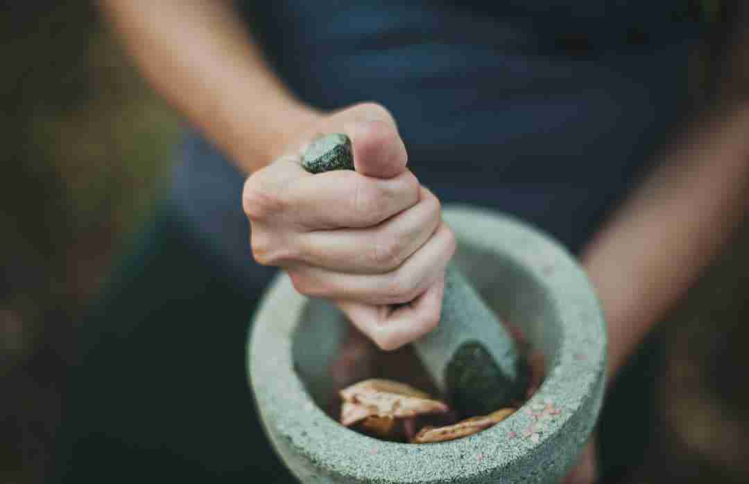 Person crushing spices in a mortar and pestle
