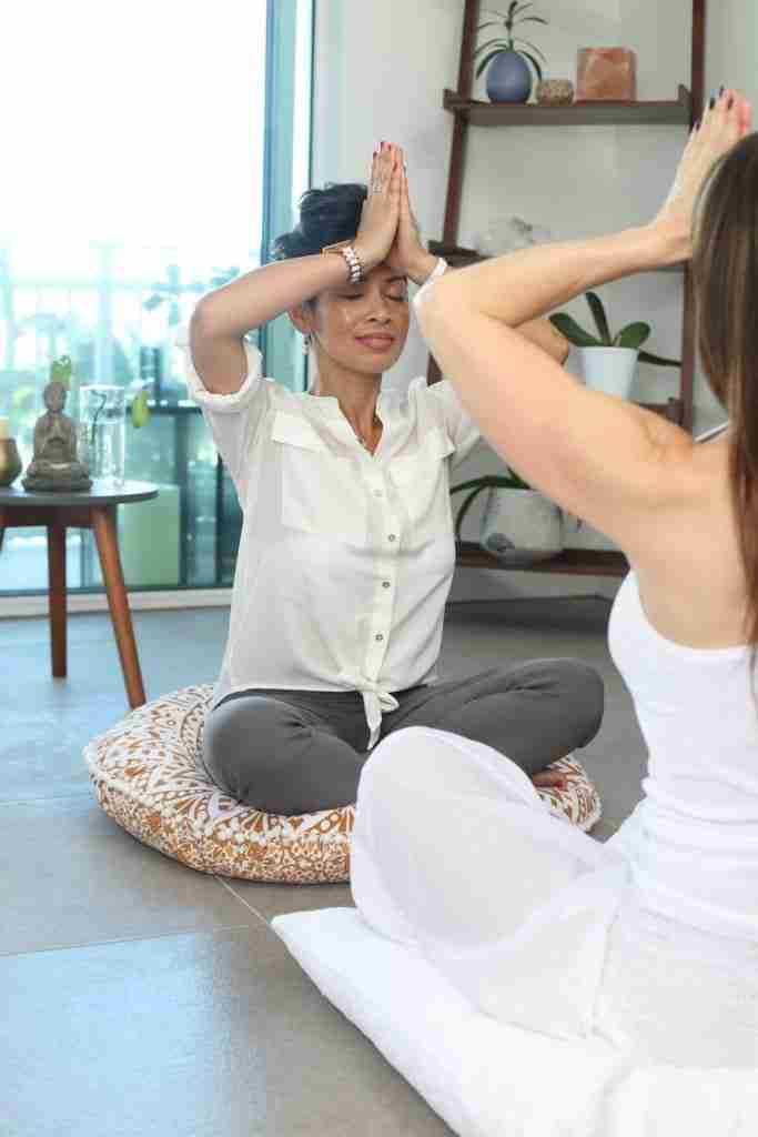 A meditation instructor guides a serene looking woman through the practice