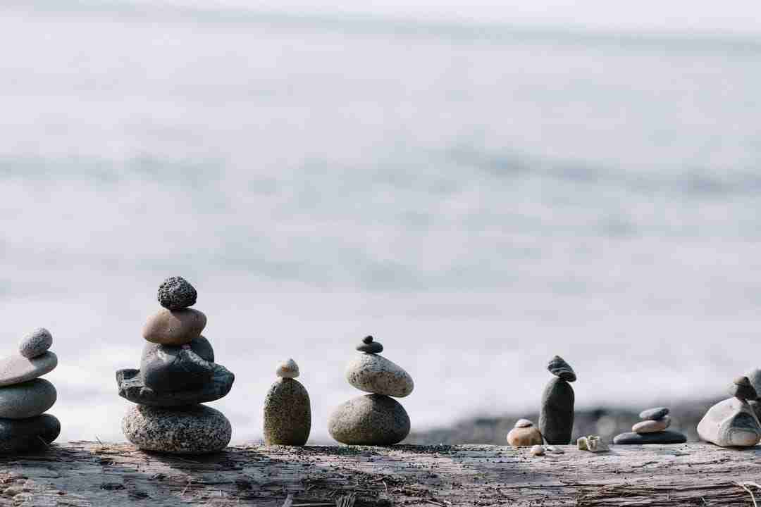 Multiple stacks of zen stones balancing on one another at a water front