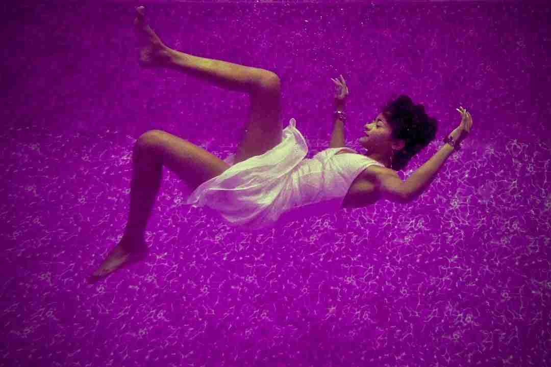 Woman floating in dream like state with purple background