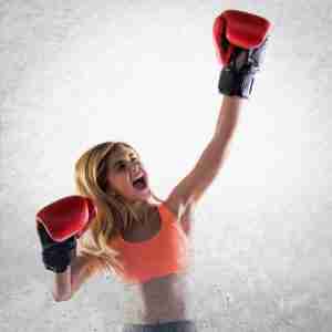 confident woman in boxing gloves shouting in victory
